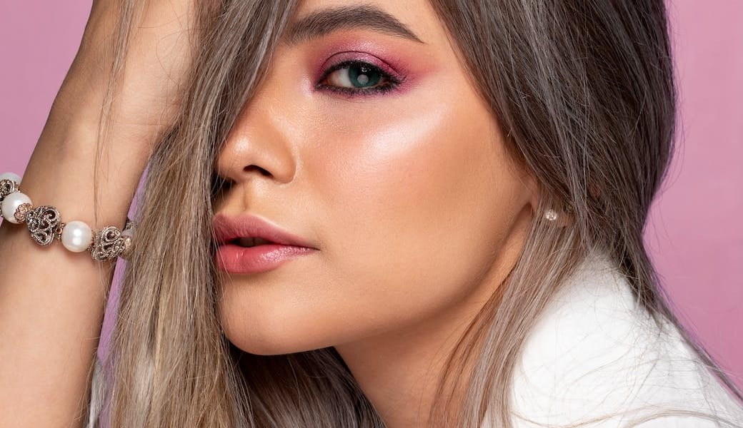 stylish model touching hair on pink background