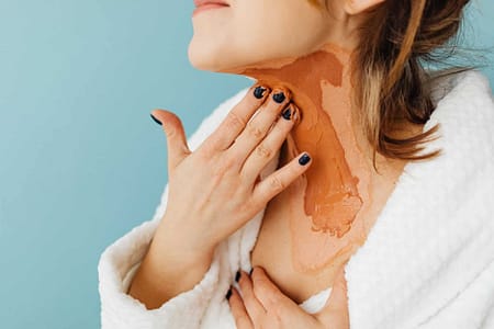 woman putting a skin treatment product on her neck