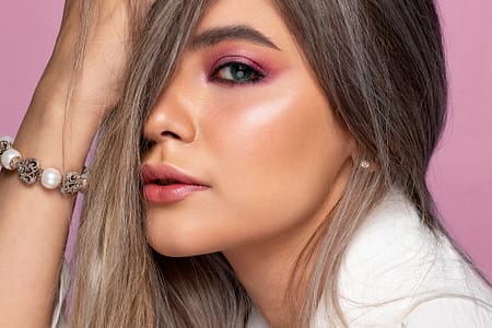 stylish model touching hair on pink background