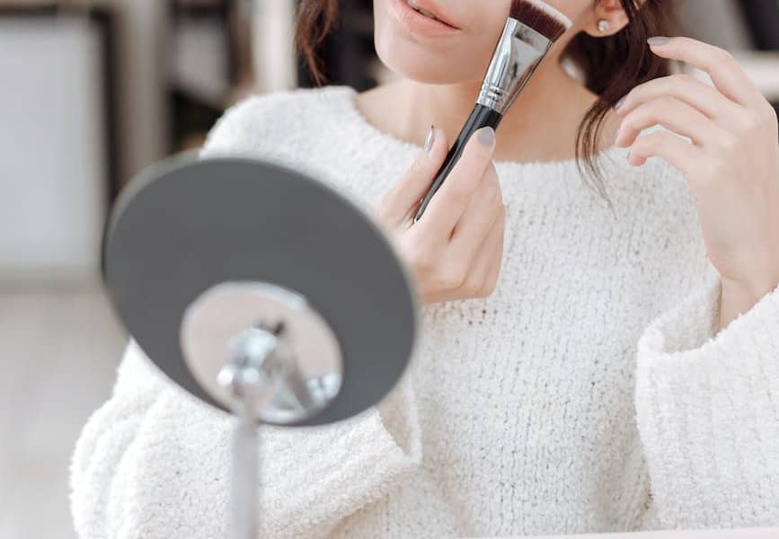 woman applying blush on on her cheek